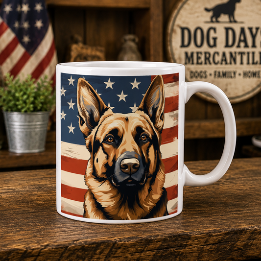 A white ceramic mug featuring a printed illustration of a German Shepherd dog against an American flag background, displayed on a rustic wooden table with a dog-themed sign in the background.